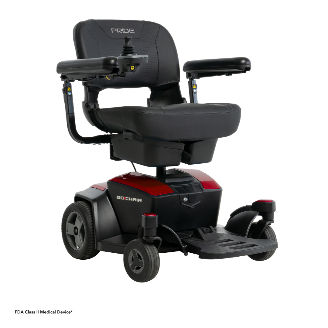 The Pride Mobility Go Chair® Portable Powerchair is a compact black and red electric wheelchair with a padded backrest, adjustable armrests, joystick control, four wheels, and a foldable seat for easy mobility and comfort.